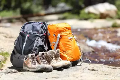 hiking boots and backpacks next to stream