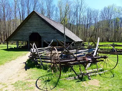 An Antique Plow Sits In Front Of An Old Barn